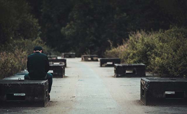 A young man sat alone on a park bench