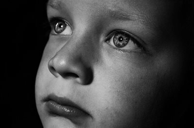 A black and white image of a child's sad face