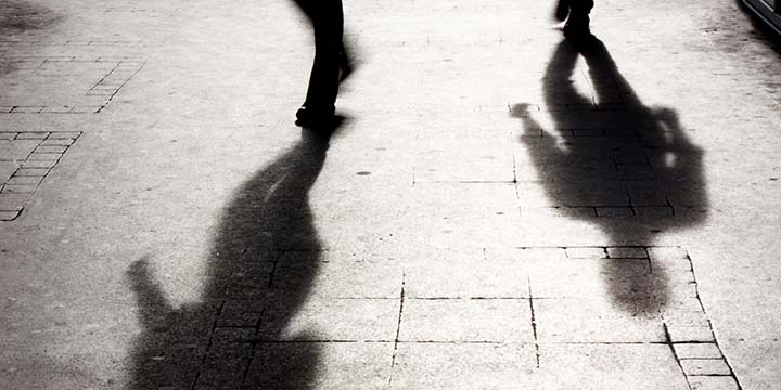 The shadows of two people walking along a street