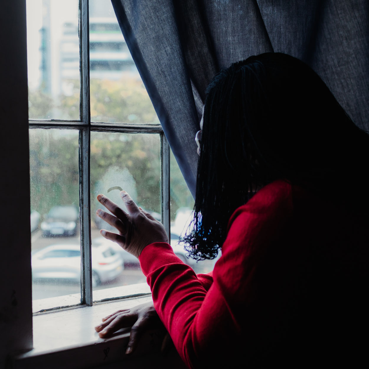 Oprah looking out of the window, drawing on a fogged patch of the glass