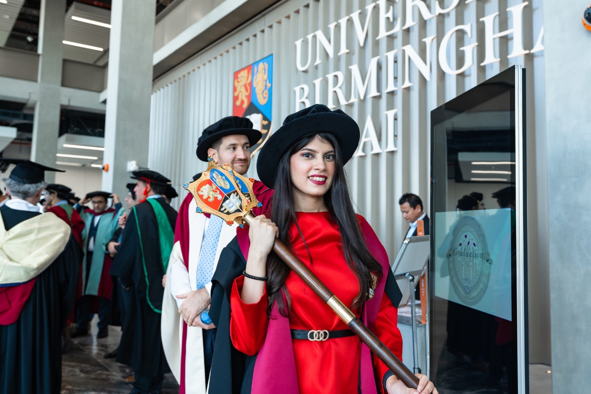 woman holding mace in graduation robes and hat