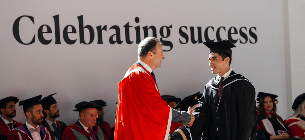 Graduate on stage shaking hands with vice chancellor