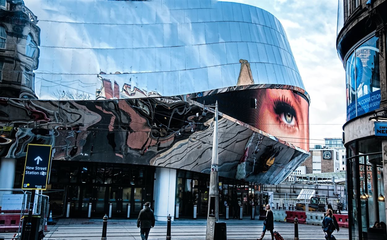Exterior of New Street train station with the surrounding buildings reflected in its metallic cladding