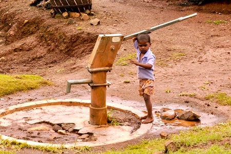 A small child operating a water pump in an Indian village