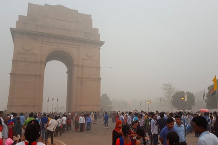 Crowds of people around the India Gate monument in New Delhi which is shrouded in smog