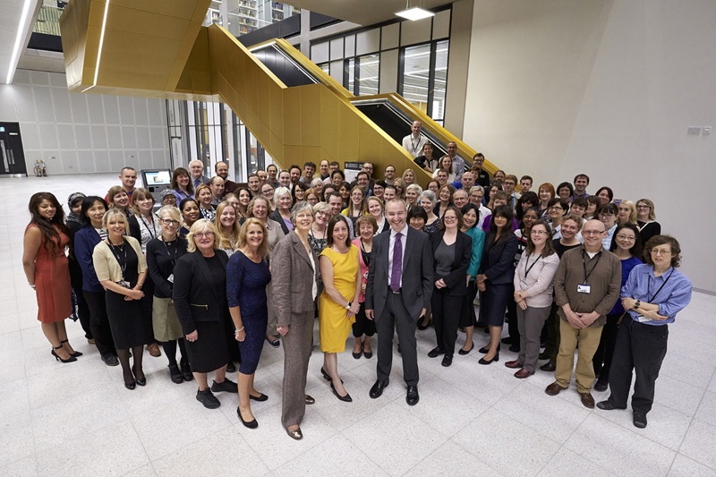 A large group of librarians stand at the foot of the iconic main staircase of the Main Library.