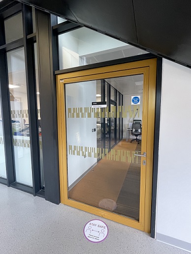Glass door to the Allport Room, just under the stairs. It's quite wide with a gold frame and gold decals across the glass.