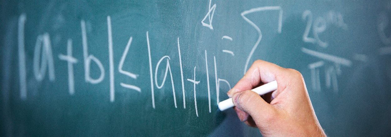 hand writing mathematical symbols on a blackboard