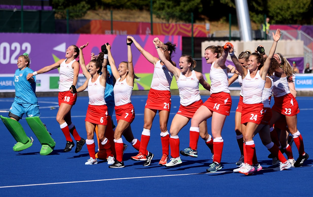 The England Women's hockey team raising their arms in triumph and celebrating their gold medal at the Birmingham 2022 Commonwealth Games