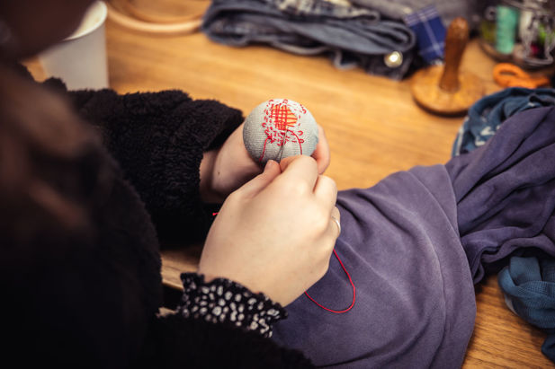 A photograph of a participant using darning techniques to repair clothing