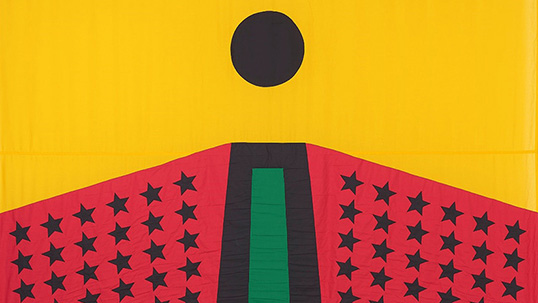 A bright yellow flag featuring a large red hexagonal shape and a black circle, resembling a man. The red shape is covered in fifty-four black stars, and a black and green stripe down the middle.
