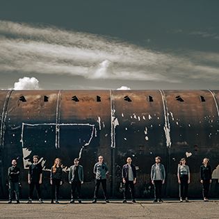 Riot Ensemble standing in front of paint splattered abandoned airplane.