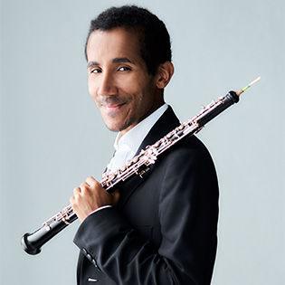 Armand Djikoloum poses holding oboe on his shoulder