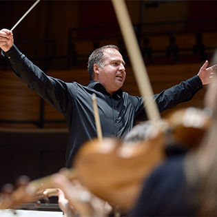 Daniele Rosina conducts holding a baton in front of musicians