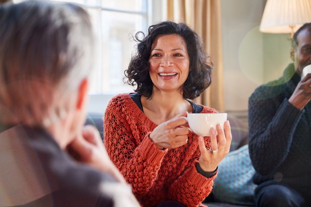 woman sat holding cup of tea talking to others
