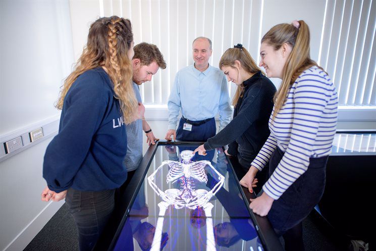 Group of students with a tutor around the anatomage table