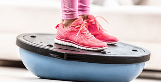 pair of feet in pink trainers on a balance board