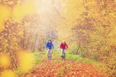 Two active seniors riding their bicycles in an Autumn forest