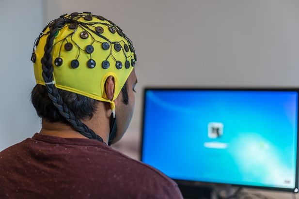 A person sat in front of a computer using magnetoencephalographic (MEG) imaging.