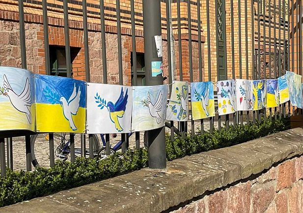 Blue and yellow posters of peace hung on a long string, attached to railings