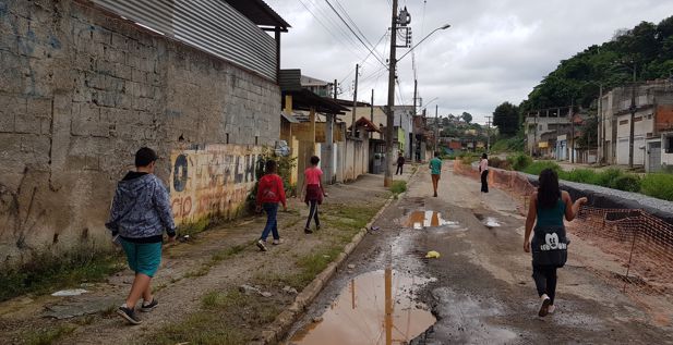 Brazilian children walking down a street full of muddy puddles in a favela