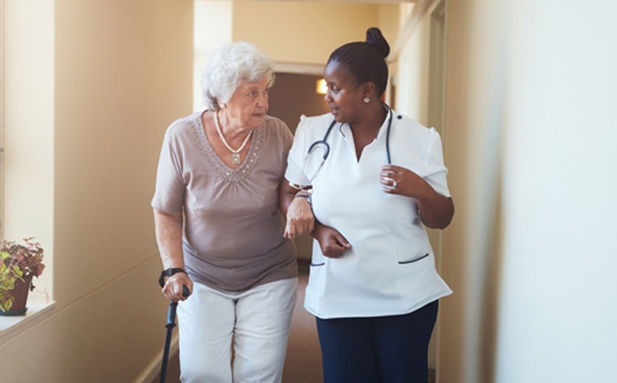 An elderly woman walking with a nurse.