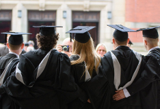 A group of graduates pose together upon graduation.