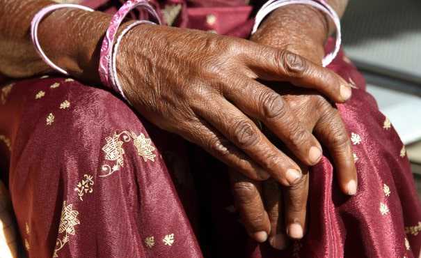 The hands of an older South Asian woman wearing traditional dress