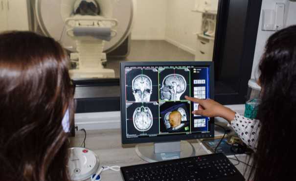 Brain scan on screen with radiographer looking at it