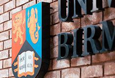 University of Birmingham crest against a redbrick wall