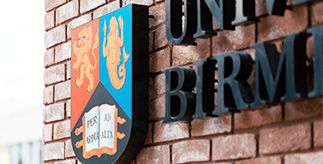 University of Birmingham crest against a redbrick wall