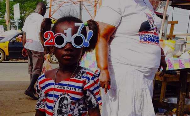Young girl wearing election campaign glasses in the shape of 2017