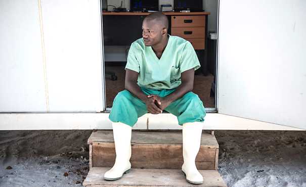 Doctor sits outside mobile laboratory in Guinea during Ebola outbreak.