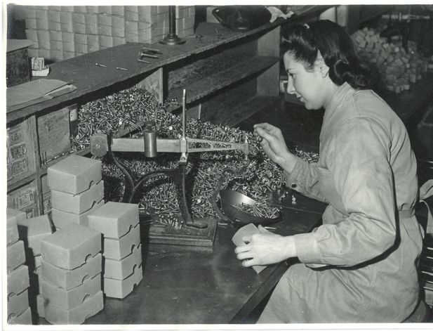 A woman packaging screws in a factory
