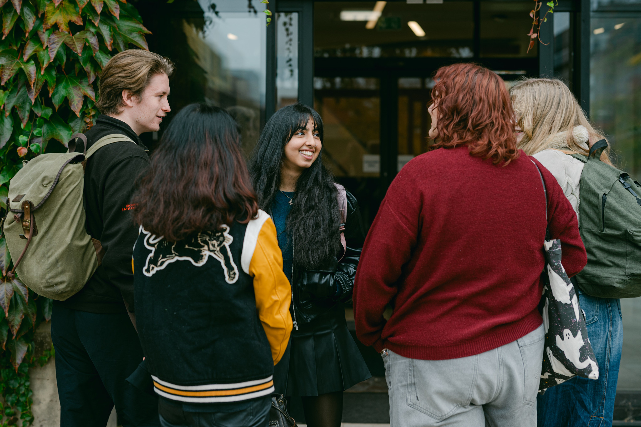 Group of 5 students in colourful clothing chat in a group
