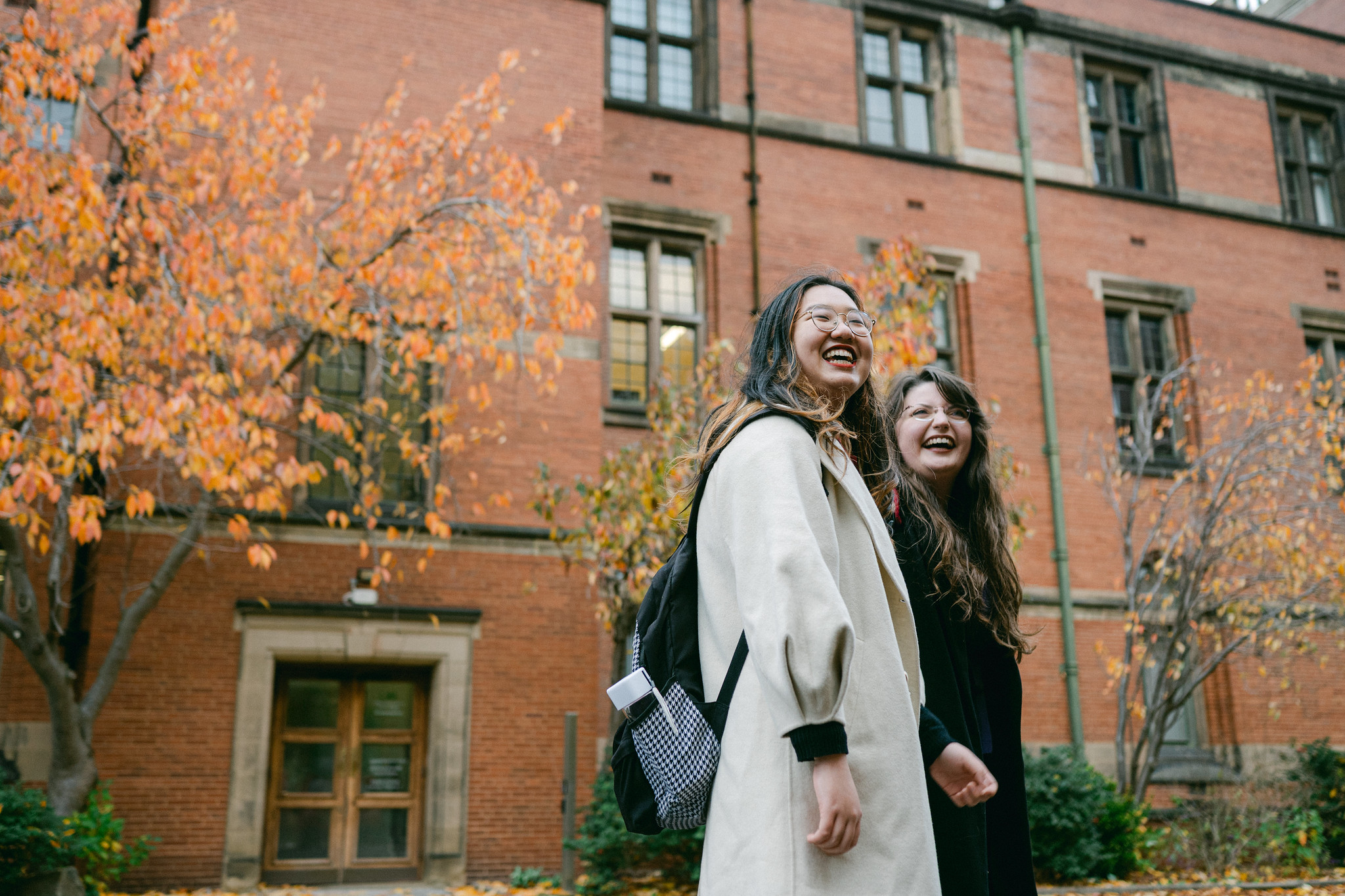 Two students walk in front of a red brick building
