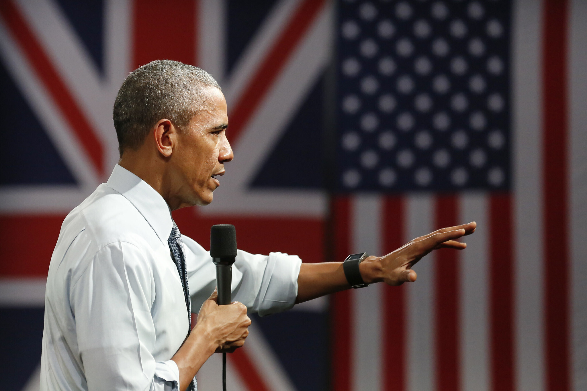 Obama speaking with a mic aside the UK and US flags