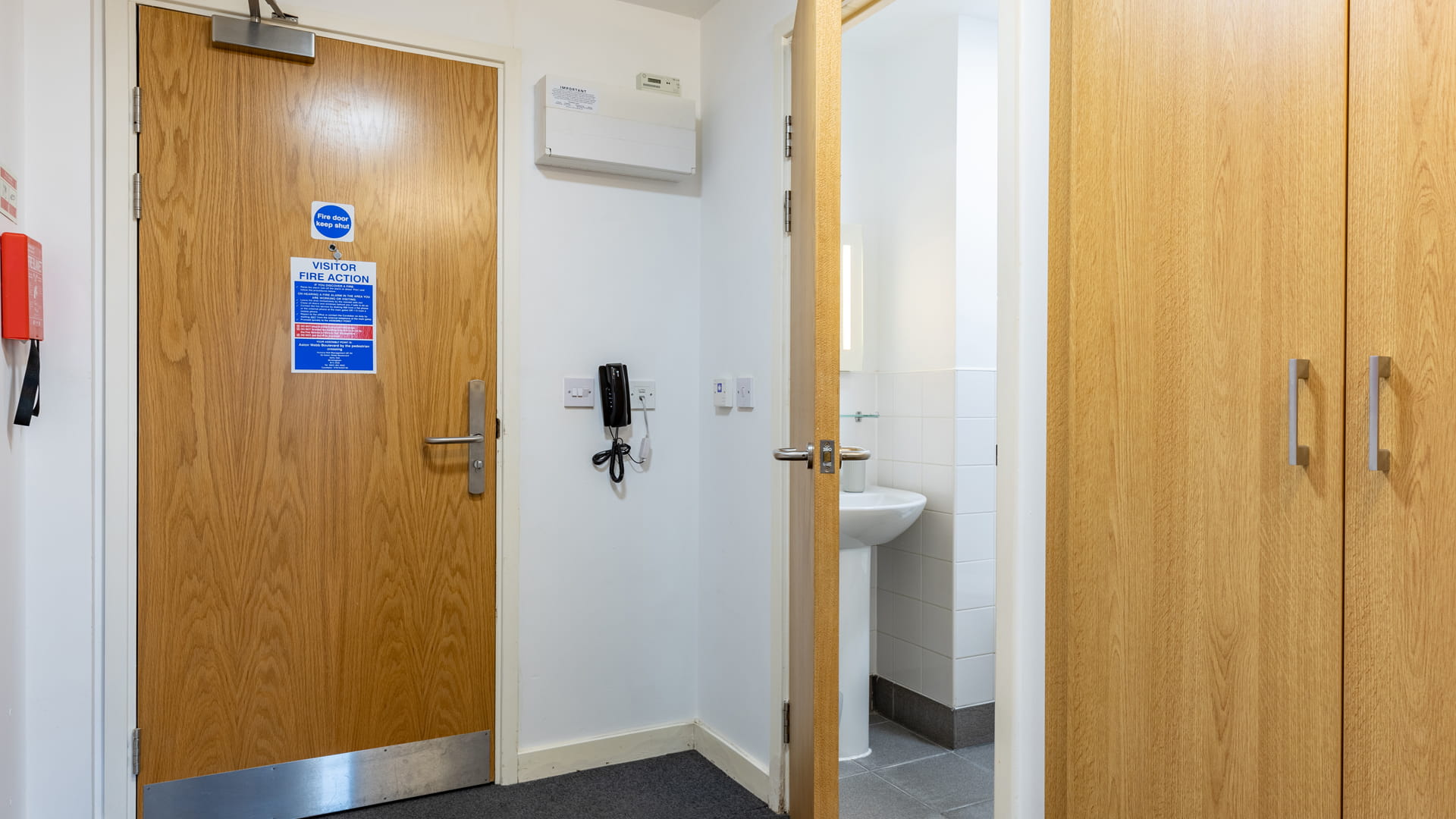 The front door next to the bathroom and a cupboard