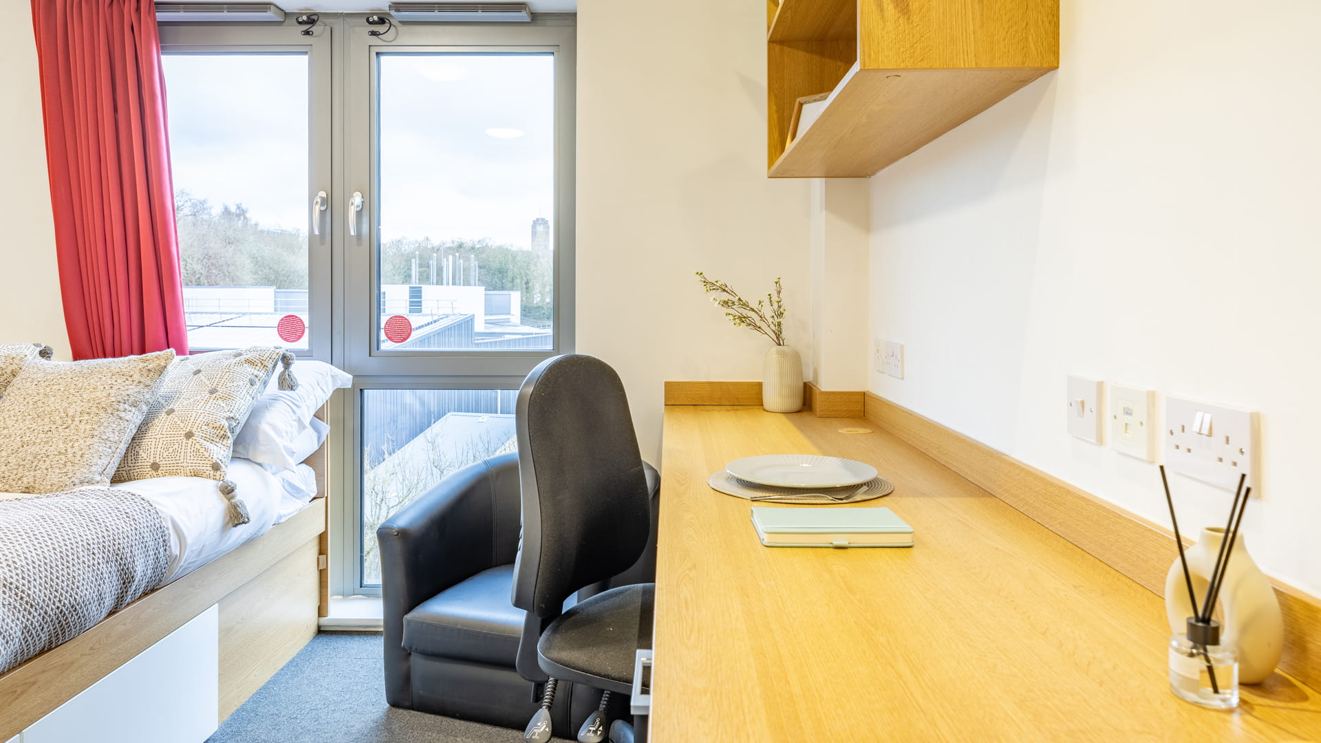 The bed next to the desk with decorations on top