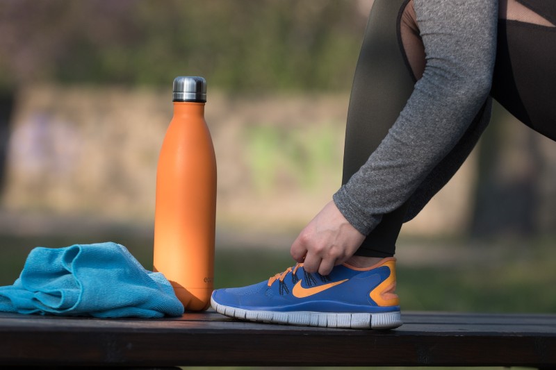 Athlete tying a shoe next to a water bottle