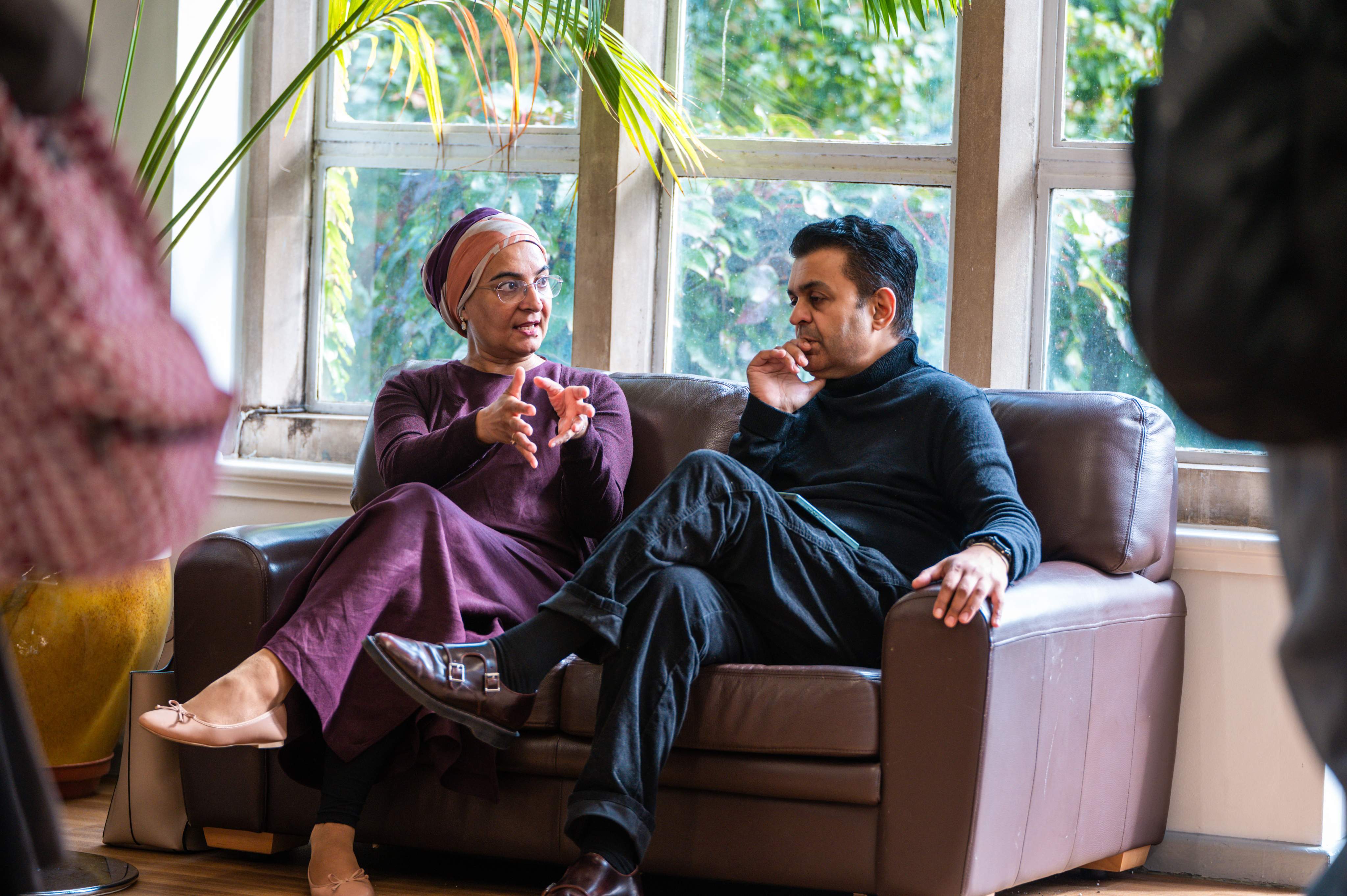 Two people are sat on a sofa in conversation
