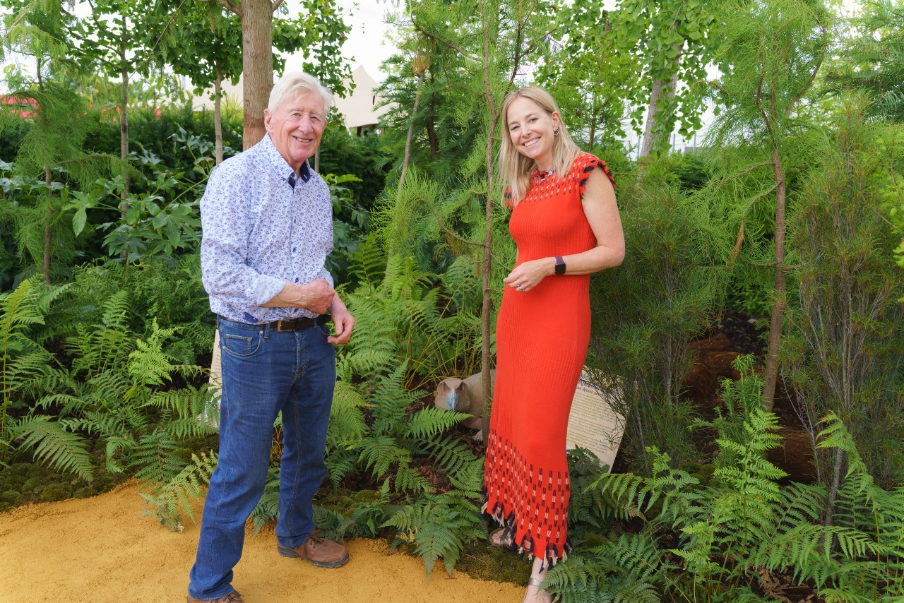 Man and woman standing in front of a garden with ferns and trees