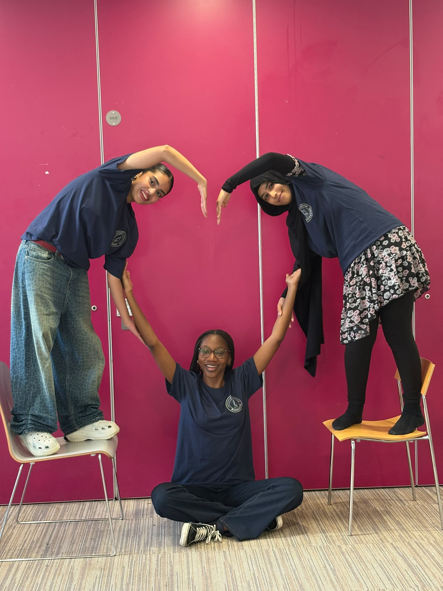 Three students posing in the shape of a heart