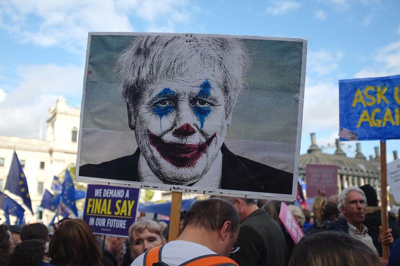 Protestor carrying placard image of Boris Johnson