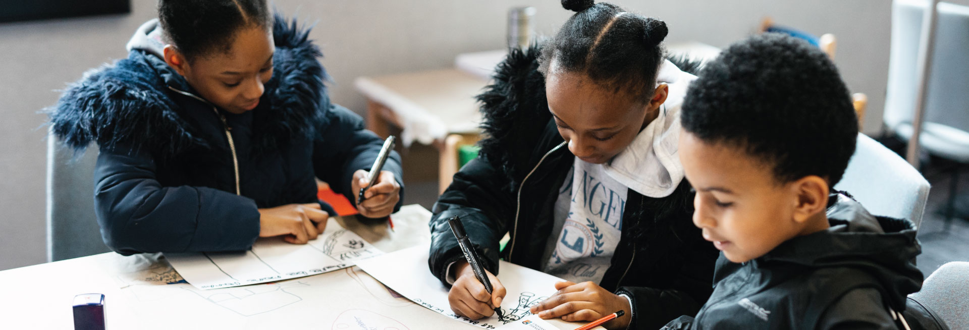 Three children work together on an activity at a table.