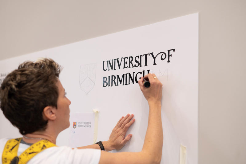 An illustrator drawing the University of Birmingham logo