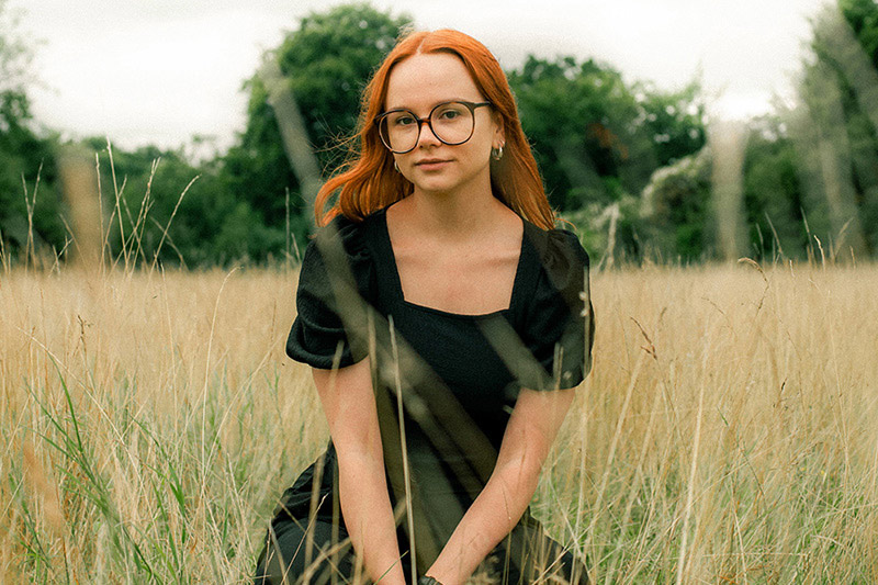 A portrait of Olivia sitting in a field