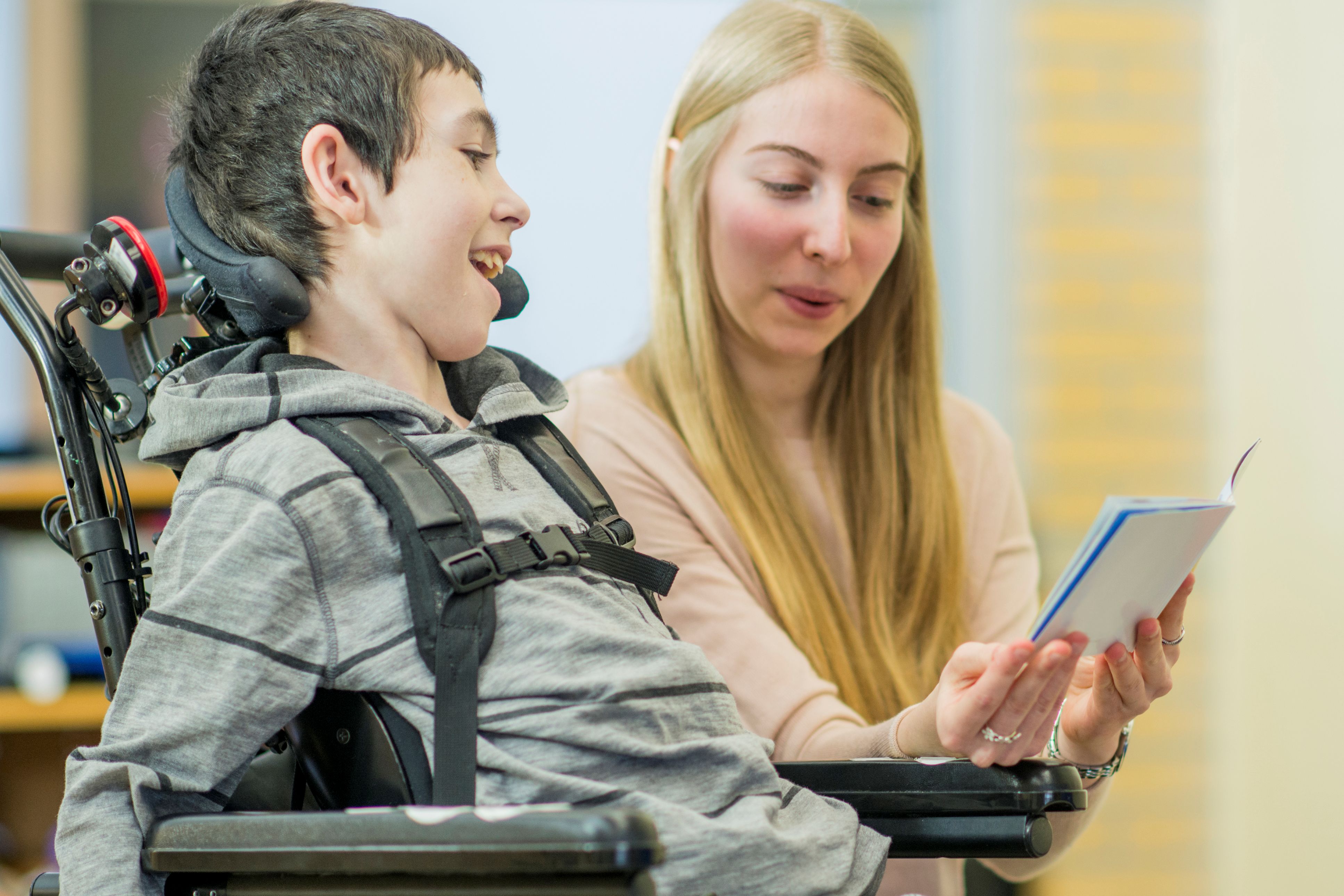 Teacher reading to child in wheelchair
