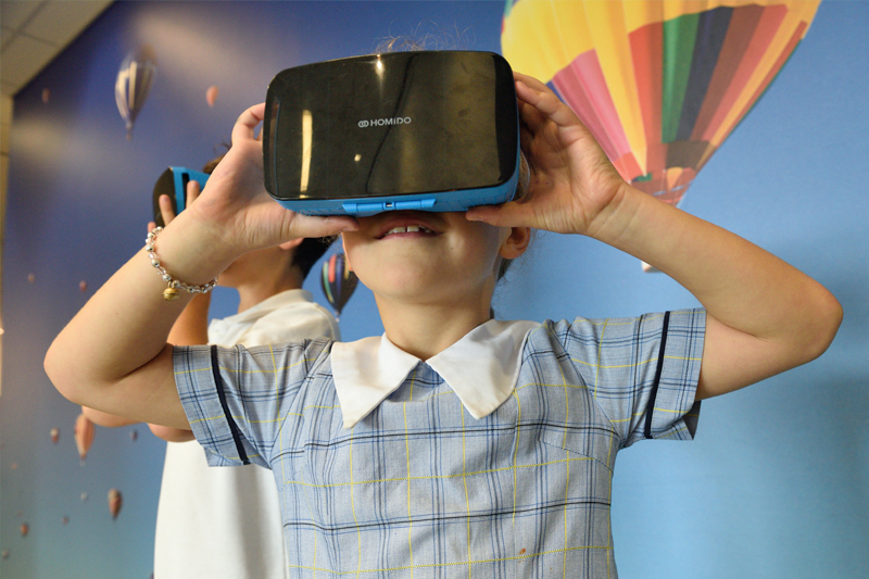 School children wearing virtual reality headsets
