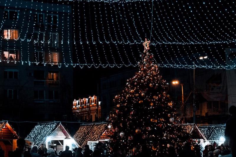A decorated Christmas tree at night, in a bustling town square